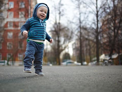 Baby in blue hoodie learning to walk